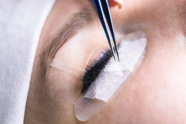 Kirpik uzatma prosedürü. Uzun kirpikli kadın gözü. Kırbaçlar, kapatın, makro, seçici odaklanma.