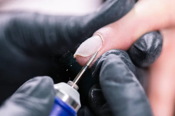 Processo manicure primo piano. Preparazione per la manicure hardware. Estetista in guanti di gomma taglia la cuticola ed elabora unghie. — Foto Stock