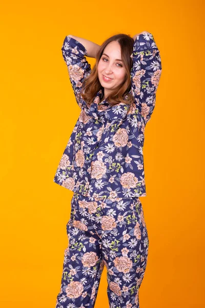 Podekscytowana młoda kobieta z kręconymi włosami w piżamie, szeroko uśmiechnięta i dobrze się bawiąca. Izolacja na żółtym tle. — Zdjęcie stockowe