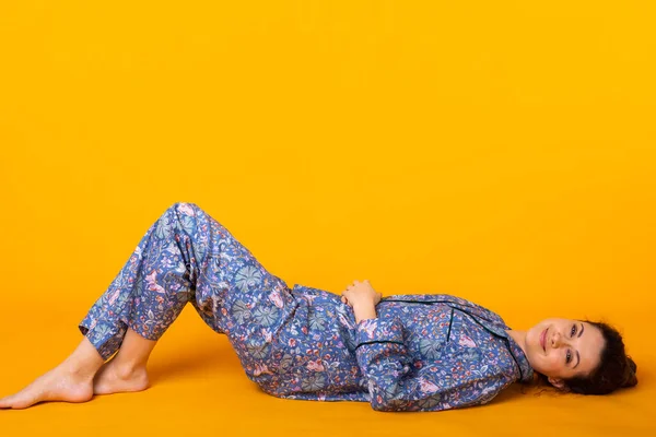 Mujer joven emocionada en ropa de casa azul, ampliamente sonriendo divertirse. Aislado sobre fondo amarillo con espacio de copia . — Foto de Stock