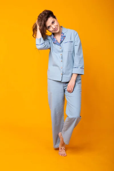 Rapariga sorridente em pijama casa desgaste posando enquanto descansa em casa isolado no fundo amarelo estúdio retrato. Relaxe conceito de estilo de vida de bom humor . — Fotografia de Stock