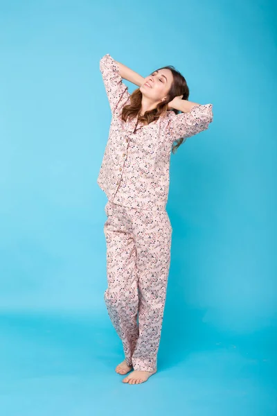 Niña posando en pijama sobre fondo azul. Relaja el buen humor, el estilo de vida y el concepto de ropa de dormir . — Foto de Stock