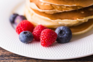 Ahşap arka planda yabanmersinli krep ve ahududu. Kahvaltı ve geleneksel yemek..