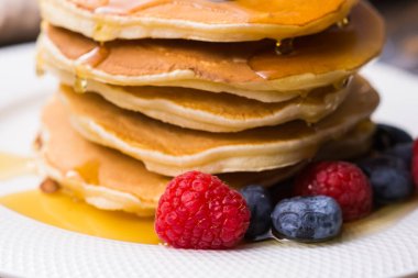 Böğürtlenli krep, ahududu ve ahşap zemin üzerinde akçaağaç pekmezi. Kahvaltı ve geleneksel yemek..
