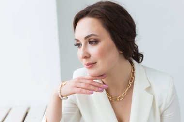 Beyaz elbiseli, makyajlı, beyaz bir odada poz veren bir kız. Moda stili stüdyo boy portresi. Zarif, zarif bir kadın..