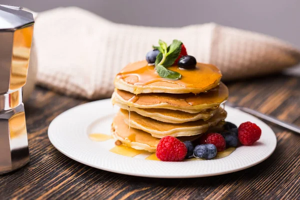 Pancakes with blueberries and raspberry and maple syrup on wooden background. Breakfast and traditional meal. — Stock Photo, Image