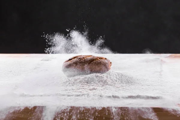 Традиционный ручной хлеб из ржаного хлеба попадает в муку. Темный фон. Концепция хлебобулочных изделий и домашнего хлеба . — стоковое фото