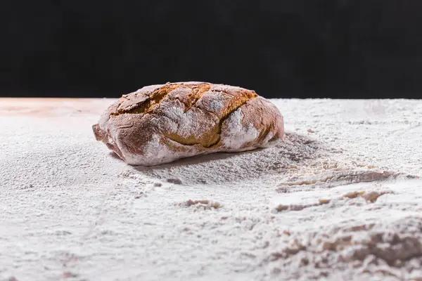 Färskt bröd på bordet närbild i mjöl placer. Färskt bröd på köksbordet. Hälsosam kost och traditionellt bageri koncept. Rustik stil. — Stockfoto