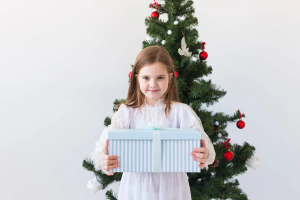 Mädchen mit Geschenkbox in der Nähe des Weihnachtsbaums. Feiertage, Weihnachten und Geschenke. — Stockfoto