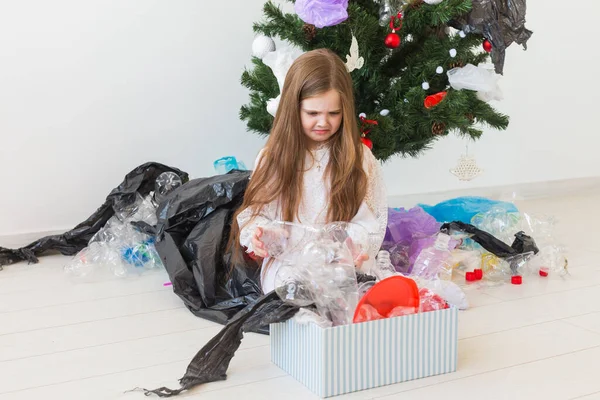 環境保護と汚染の概念。クリスマスツリーの背景にプラスチックごみと悲しい子キャリアボックス. — ストック写真