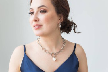 Zarif saç stili, lüks mücevherleri ve bijouterisi olan güzel bir genç kadının yakın plan portresi..