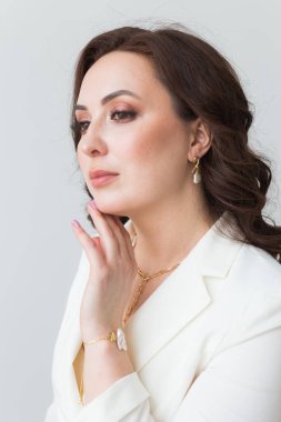 Zarif saç stili, lüks mücevherleri ve bijouterisi olan güzel bir genç kadının yakın plan portresi..