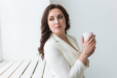 Güzel kadın ellerinin kapuçino dolu büyük beyaz bir fincan kahve tutmasını..