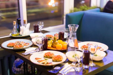 Ziyafet masasına servis edilmiş. Peçeteli, bardaklı ve salatalı şarap bardakları.