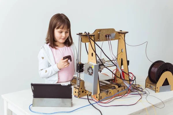 Linda chica con persianas impresas en 3D está viendo su impresora 3d, ya que imprime su modelo 3d . — Foto de Stock