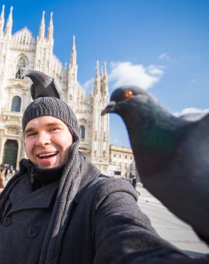Seyahat, İtalya ve eğlence konsepti - Mutlu turist Duomo Katedrali önünde güvercinlerle kendi portresini çekiyor, Milano
