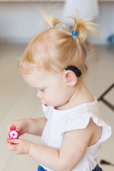 En liten flicka med hörapparat. Begreppet barn med funktionshinder, funktionshinder och dövhet. — Stockfoto