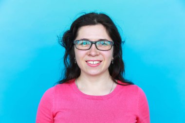 Mavi arka planda gözlüğü olan neşeli, genç bir bayan öğrenci..