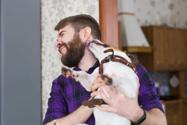 Primer plano retrato guapo joven hipster hombre juega y ama a su buen amigo perro en casa. Emociones humanas positivas, expresión facial, sentimientos . — Foto de Stock