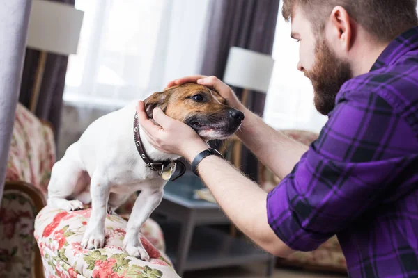 Primer plano retrato guapo joven hipster hombre juega y ama a su buen amigo perro en casa. Emociones humanas positivas, expresión facial, sentimientos . — Foto de Stock