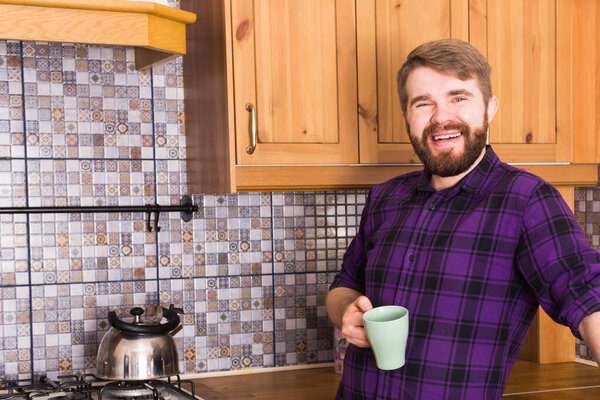 Bearded man with kettle making tea for breakfast at home kitchen. Morning and breakfast concept.
