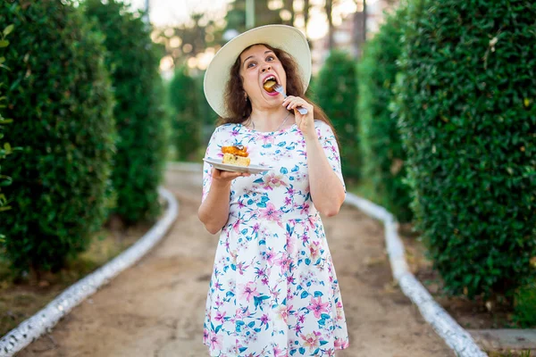 Πολύ αστεία γυναίκα τρώει την τούρτα στο πάρκο. Τρόφιμα, διατροφή, ανθυγιεινά τρόφιμα και γλυκιά έννοια. Εξάρτηση ζάχαρης. — Φωτογραφία Αρχείου