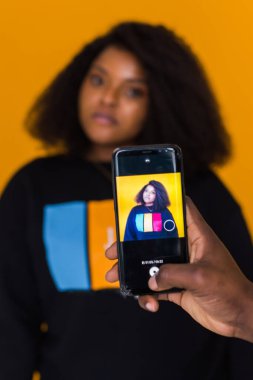 Genç adam içeride Afro-Amerikan güzel kız arkadaşının fotoğrafını çekiyor. Teknoloji ve siyah insanlar kavramı.