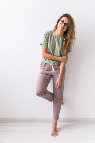 Mujer atractiva joven vestida con hermoso pijama colorido posando como modelo en su sala de estar. Ropa de dormir cómoda, relajación en el hogar y concepto de moda femenina . — Foto de Stock