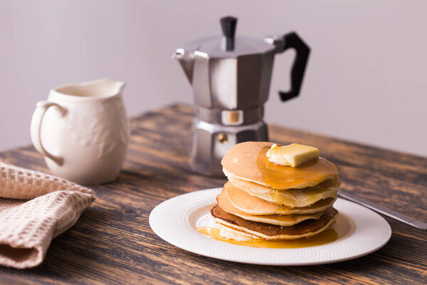 Small pancakes with maple syrup and butter on wooden table. Breakfast concept.