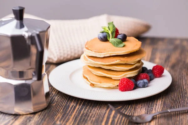 Pile of pancakes with blueberries and raspberries for breakfast on wooden table. — Stock Photo, Image