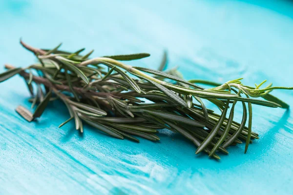 Close-up fragrant rosemary herbs on white on turquoise wooden background. — Stock Photo, Image