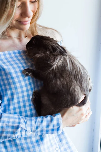 Mascotas y concepto de Pascua - Chica feliz abrazando conejo marrón en casa . — Foto de Stock