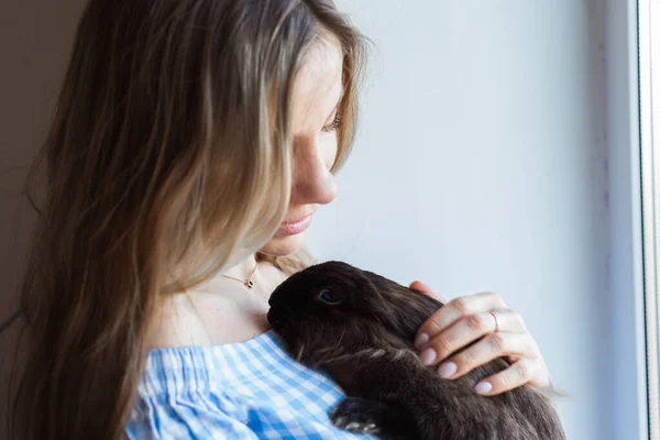 Mascotas y concepto de Pascua - Chica feliz abrazando conejo marrón en casa . — Foto de Stock