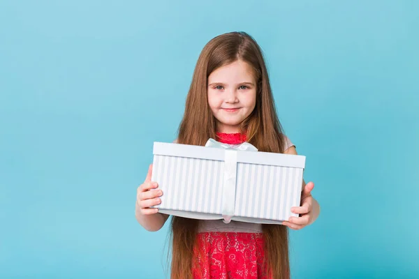 Niño feliz sosteniendo regalos de cumpleaños sobre un fondo azul. En Navidad. Cumpleaños de los niños . —  Fotos de Stock