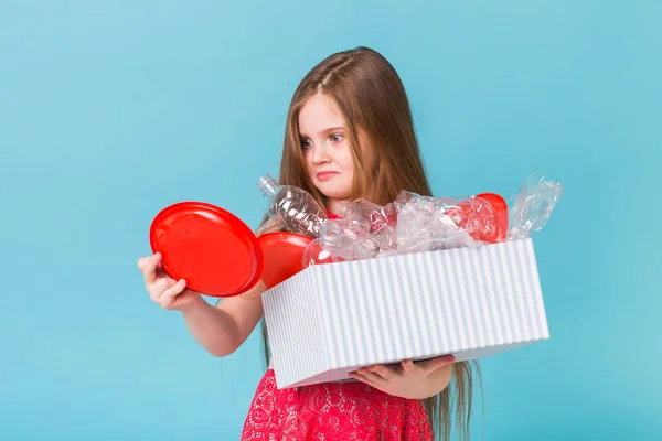 Protección del medio ambiente y concepto de contaminación. Caja de transporte infantil sorprendida con basura plástica sobre fondo azul . —  Fotos de Stock