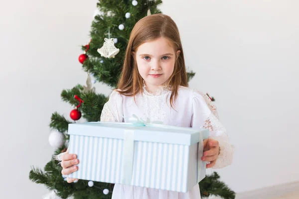 Mädchen mit Geschenkbox in der Nähe des Weihnachtsbaums. Feiertage, Weihnachten und Geschenke. — Stockfoto