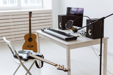 Mikrofon, bilgisayar ve müzik aletleri gitarlar ve piyano arka planı. Ev kaydı stüdyo konsepti.