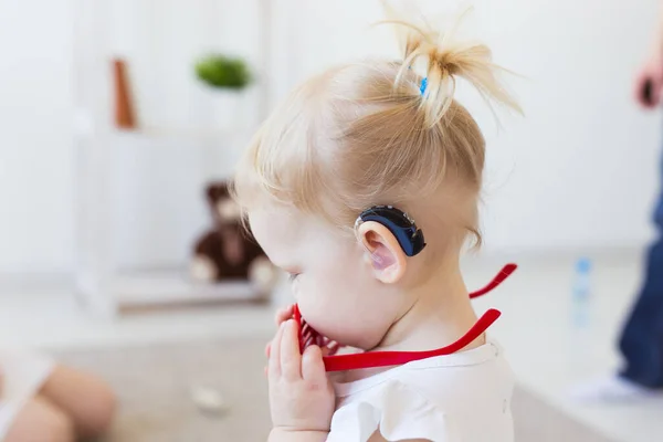 En liten flicka med hörapparat. Begreppet barn med funktionshinder, funktionshinder och dövhet. — Stockfoto
