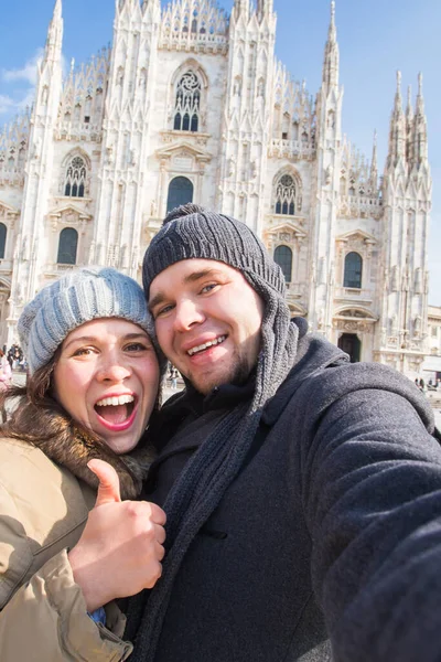 Travel, Italy and funny couple concept - Happy tourists taking a self portrait with pigeons in front of Duomo cathedral, Milan