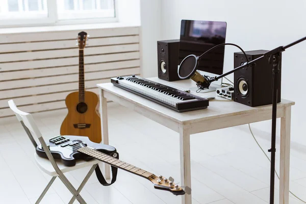Mikrofon, dator och musikalisk utrustning gitarrer och piano bakgrund. Heminspelning studio koncept. — Stockfoto