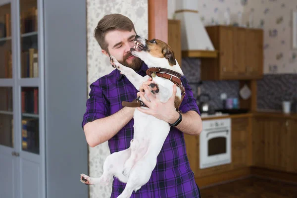 Joyeux jeune homme assis avec son chien à la maison. Propriétaire d'animal, animaux et concept d'amitié . — Photo