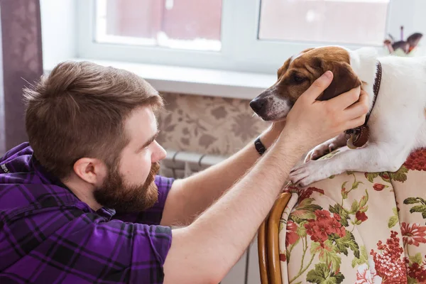 Primer plano retrato guapo joven hipster hombre juega y ama a su buen amigo perro en casa. Emociones humanas positivas, expresión facial, sentimientos . — Foto de Stock