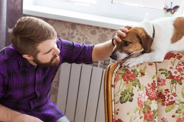 Feliz joven sentado con su perro en casa. Propietario de mascotas, animales y concepto de amistad . — Foto de Stock