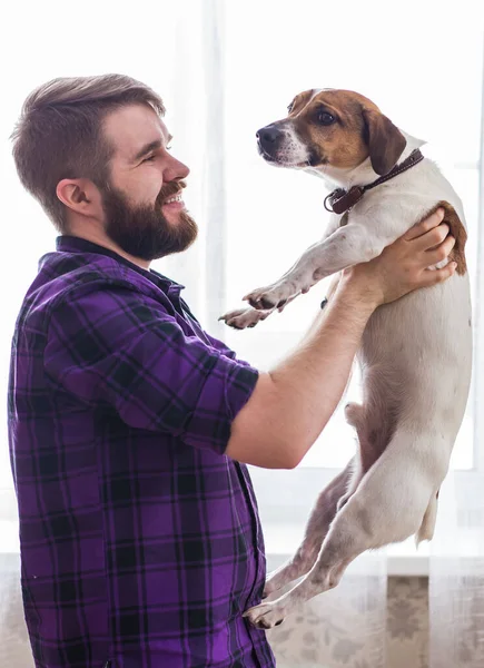 Glad ung man sitter med sin hund hemma. Djurägare, djur och vänskap. — Stockfoto