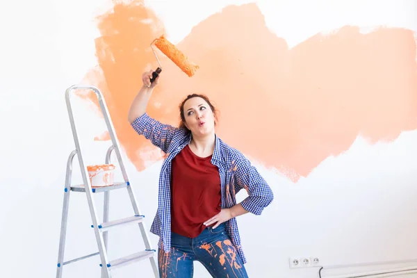 Repair in the apartment. Dancing funny woman paints the wall with paint. — Stock Photo, Image