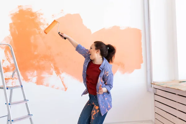 在她的新公寓里跳舞的有趣的女人画墙壁。翻修、重新装修和修理概念. — 图库照片