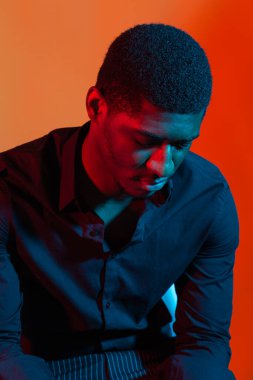 Mavi ve kırmızı ışıklı arka planda poz veren Afro-Amerikan stil adamı.