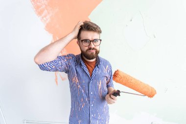 Yeni evin duvarlarını boyayan kafası karışmış komik bir adam. Yenileme, onarım ve yeniden dekorasyon konsepti.
