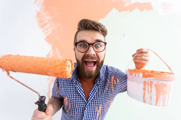 Funny man with painting roller indoors. Redecoration, renovation, apartment repair and refreshment concept. — Stock Photo, Image
