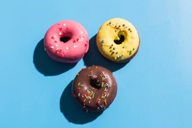 Parlak mavi arka planda renkli yuvarlak çörekler. Tatlı çörekler. Moda güneş ışığı yaz şablonu Minimum yaz konsepti.